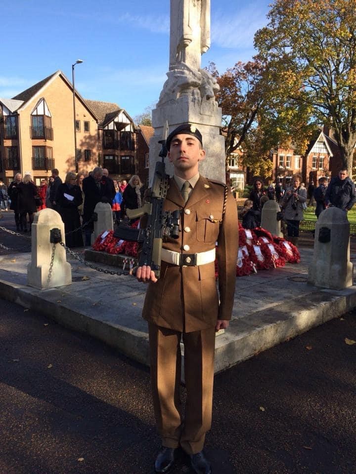 Private Lionetti stands to attention in front of war memorial
