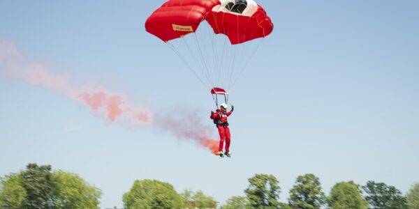 parachuter lands with smoke with crowd watching