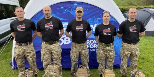 Grant for 2623 Squadron RAF Reserves team ready to take part in Walking with the wounded Cumbrian Challenge standing with backpacks in front of RAF Reserves gazebo in field