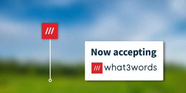 a blurred landscape of fields and blue sky with the Now Accepting what3words badge superimposed