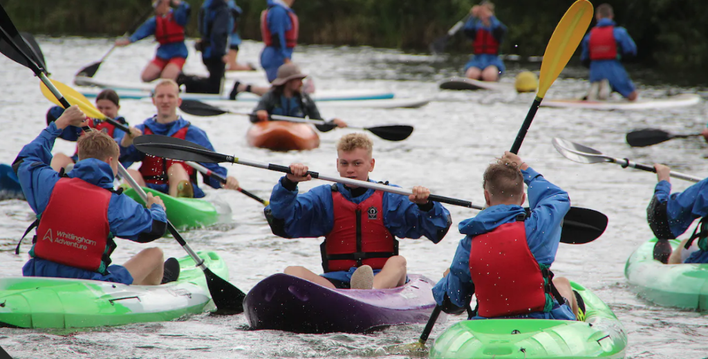 cadets in kayaks paddling past each other on the water