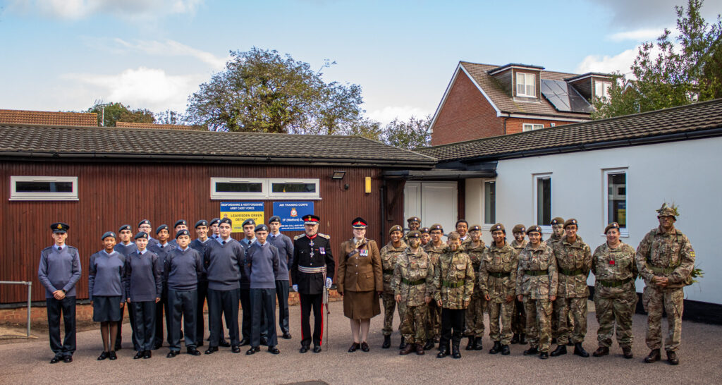 Air cadets and army cadets stand side by side in front of their new joint cadet centre in North Watford, with HM Lord-Lieutenant of Hertfordshire Robert Voss and the Cadet Force Adult volunteers at the opening event of Leavesden Green Joint Cadet Centre.